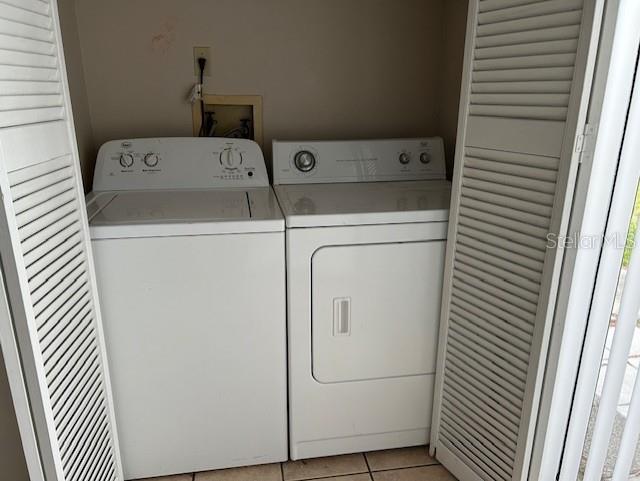 laundry room featuring laundry area, washer and clothes dryer, and light tile patterned floors