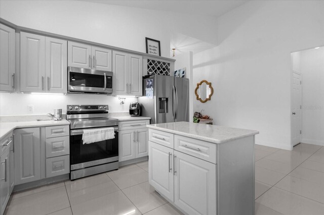 kitchen featuring light tile patterned floors, stainless steel appliances, vaulted ceiling, and a kitchen island