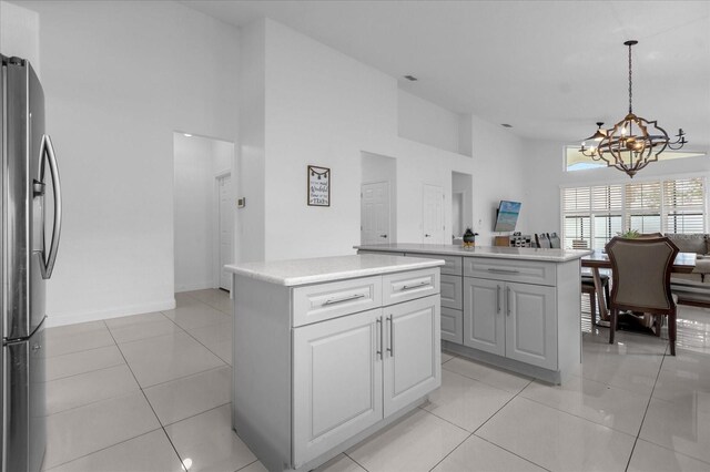 kitchen featuring a center island, high vaulted ceiling, stainless steel refrigerator, and hanging light fixtures