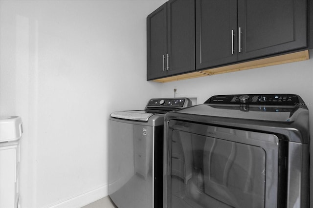 laundry room featuring washer and dryer and cabinets