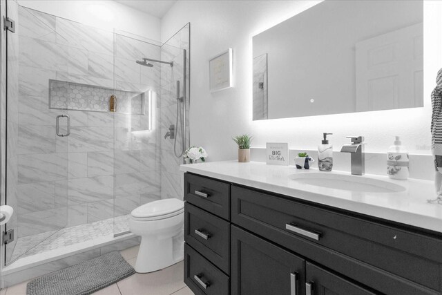 bathroom with tile patterned floors, vanity, toilet, and walk in shower