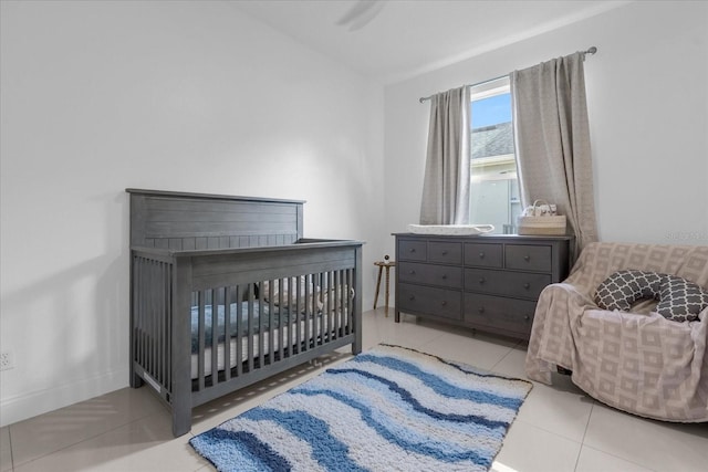 bedroom featuring a crib, ceiling fan, and light tile patterned flooring