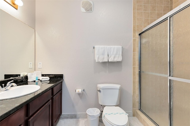 bathroom with vanity, a shower with shower door, and toilet