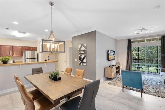 dining space with crown molding, track lighting, and an inviting chandelier