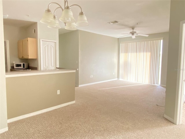 spare room with light colored carpet and ceiling fan with notable chandelier