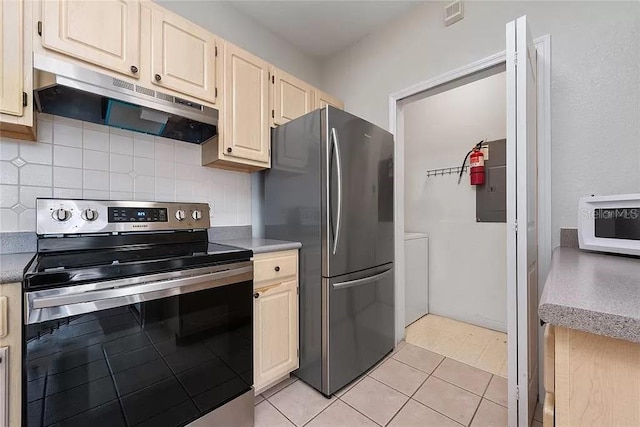 kitchen featuring light tile patterned flooring, backsplash, and appliances with stainless steel finishes