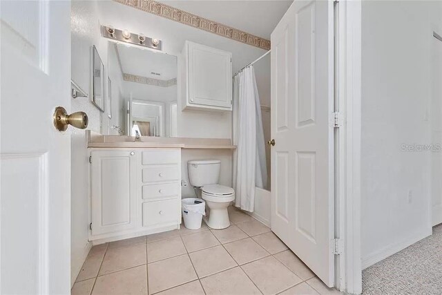 full bathroom featuring toilet, vanity, tile patterned floors, and shower / bathtub combination with curtain