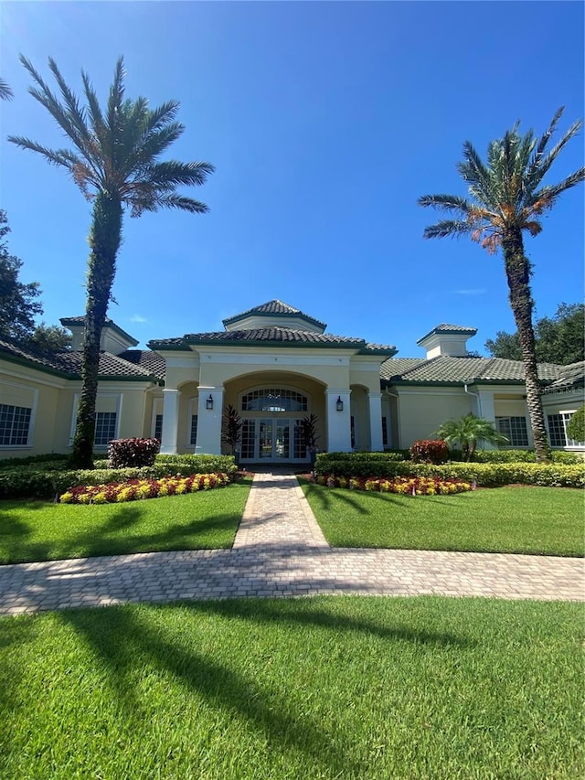 mediterranean / spanish-style house featuring french doors and a front lawn