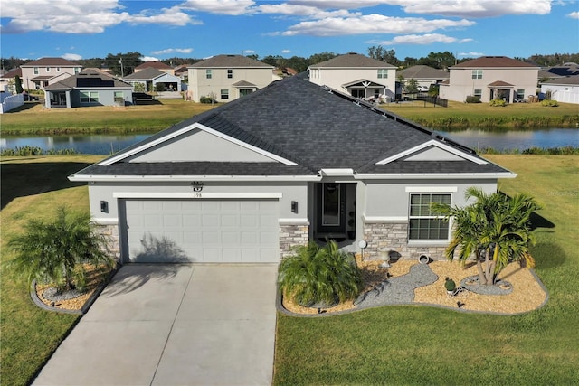 view of front facade with a water view, a front yard, and a garage