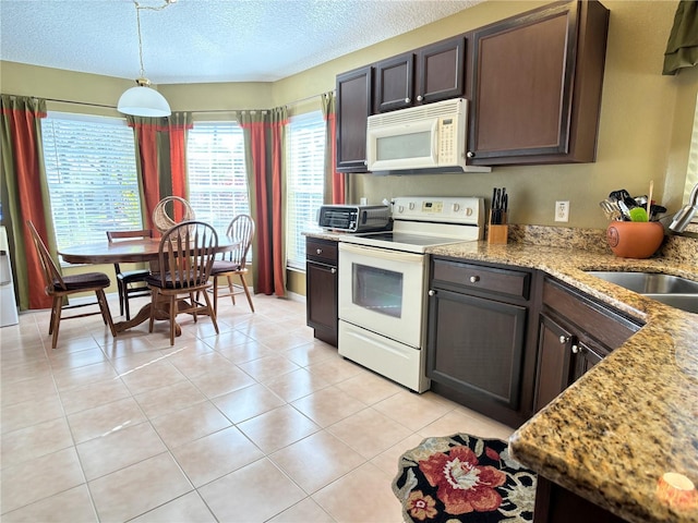 kitchen with light tile patterned floors, sink, dark brown cabinets, and white appliances