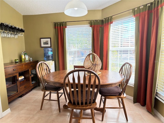 tiled dining room featuring a textured ceiling and a healthy amount of sunlight