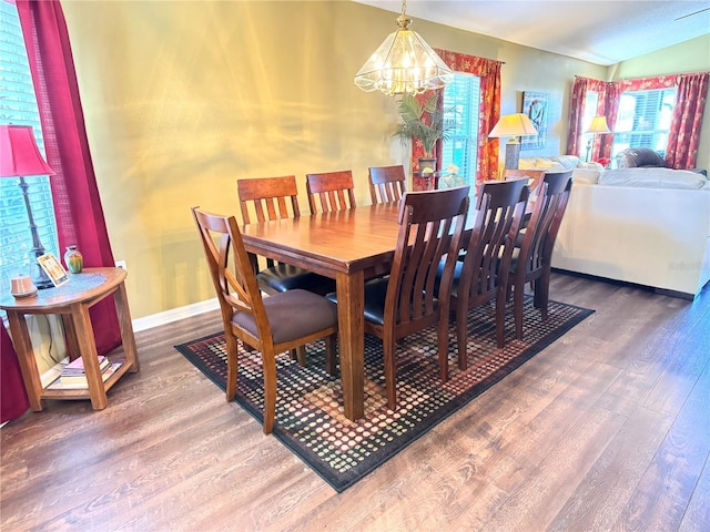 dining room with a chandelier, lofted ceiling, and hardwood / wood-style flooring