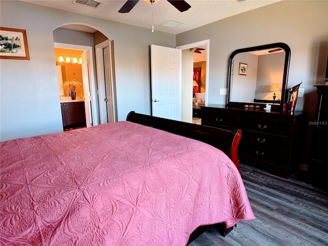 bedroom with ceiling fan, a textured ceiling, wood-type flooring, and ensuite bath