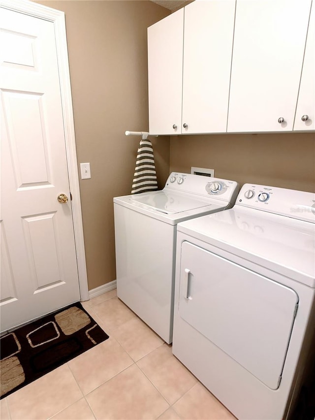 washroom with cabinets, light tile patterned flooring, and washer and clothes dryer