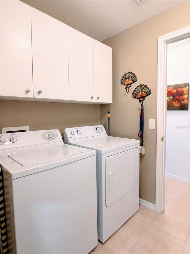 clothes washing area featuring cabinets, a textured ceiling, light tile patterned floors, and independent washer and dryer