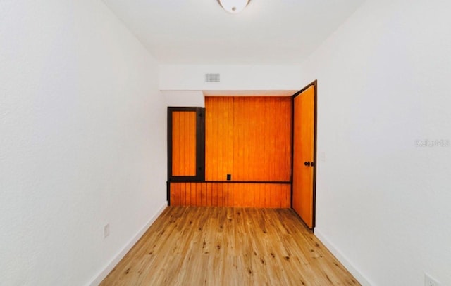 empty room featuring light wood-style flooring, visible vents, and baseboards