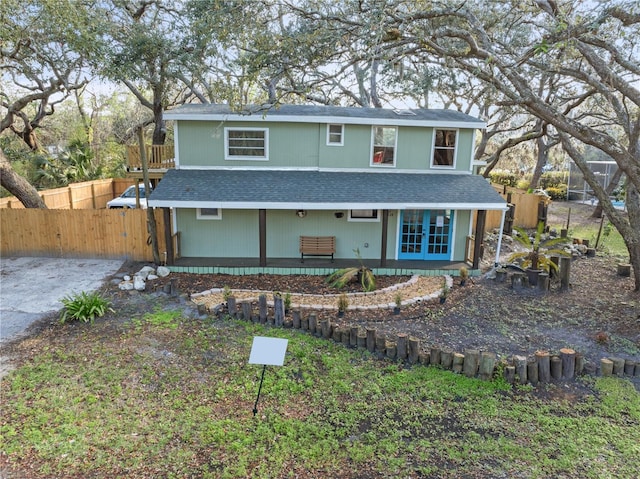 traditional home with a shingled roof, fence, aphalt driveway, and french doors