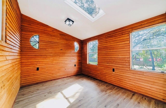 unfurnished room featuring lofted ceiling with skylight and wood finished floors