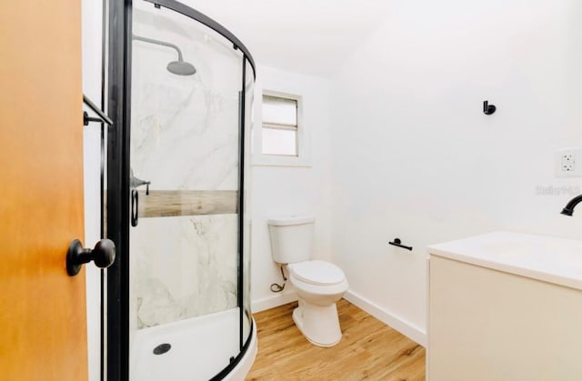 bathroom with wood finished floors, a marble finish shower, toilet, and baseboards