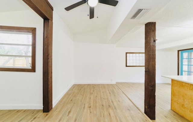 empty room with lofted ceiling, light wood-style floors, baseboards, and visible vents