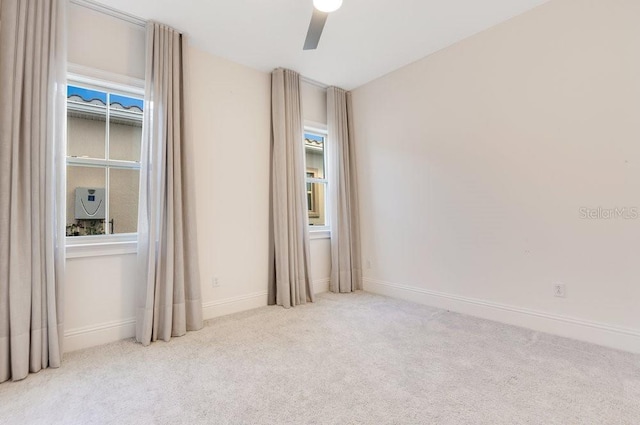 empty room featuring light carpet, baseboards, and a ceiling fan