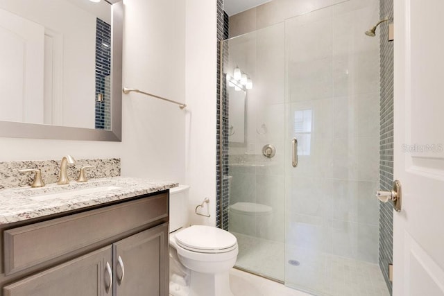 bathroom featuring toilet, a stall shower, and vanity