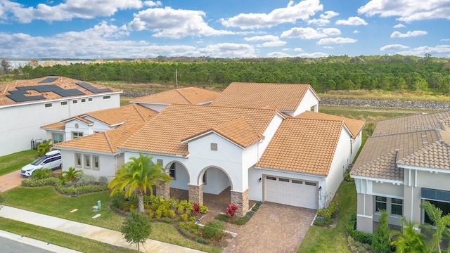 view of front of home featuring decorative driveway, an attached garage, a tile roof, and stucco siding