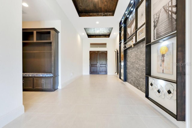 hall featuring recessed lighting, a raised ceiling, and baseboards