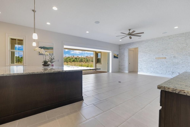 kitchen featuring wallpapered walls, open floor plan, decorative light fixtures, light stone countertops, and recessed lighting