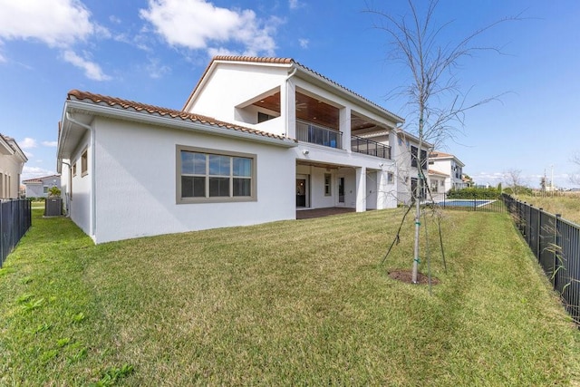 rear view of property featuring a lawn, a balcony, a tiled roof, fence, and central air condition unit