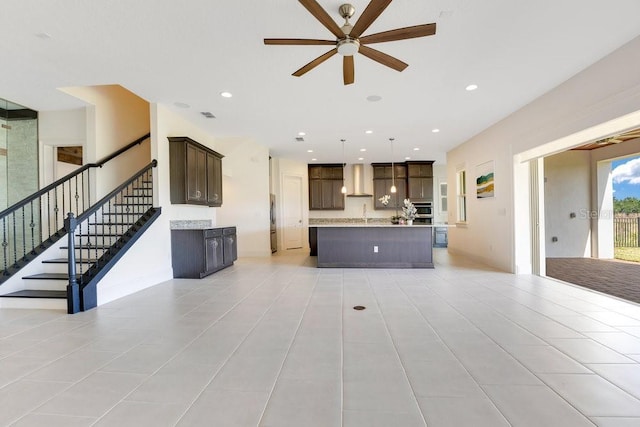 unfurnished living room with ceiling fan, light tile patterned floors, recessed lighting, visible vents, and stairway