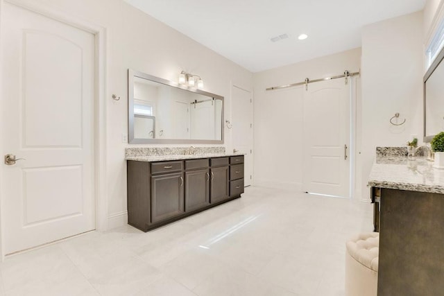 full bathroom with baseboards, visible vents, two vanities, and a sink