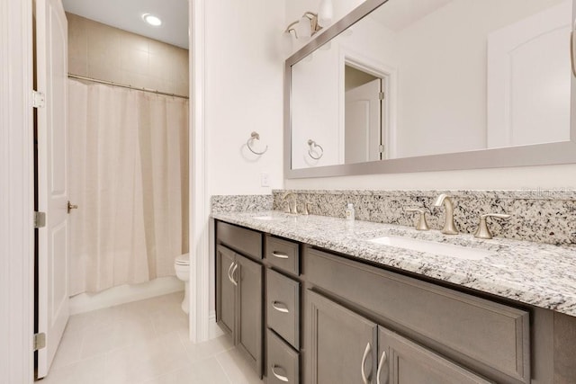 bathroom featuring tile patterned flooring, a sink, toilet, and double vanity