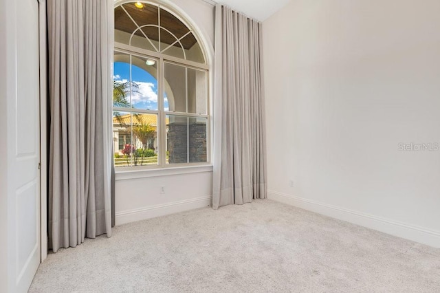 spare room with light colored carpet and baseboards