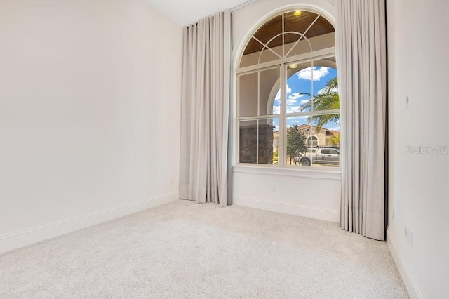 empty room with baseboards and light colored carpet