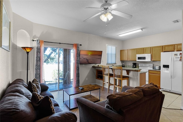 living room with ceiling fan, light tile patterned flooring, and a textured ceiling