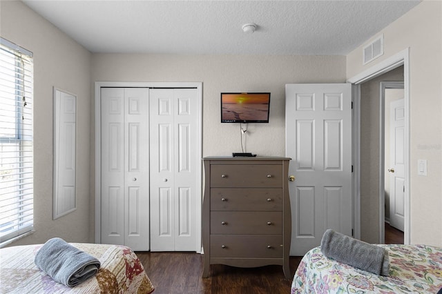 bedroom with a textured ceiling, dark hardwood / wood-style flooring, and a closet