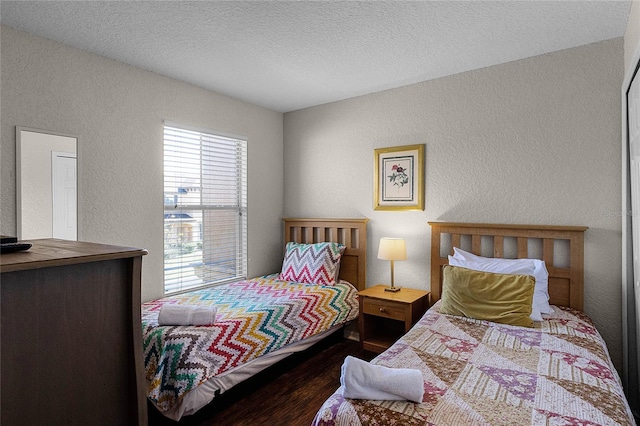 bedroom with a textured ceiling and dark wood-type flooring