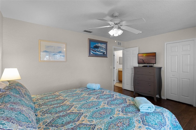 bedroom with a textured ceiling, dark hardwood / wood-style flooring, a closet, and ceiling fan