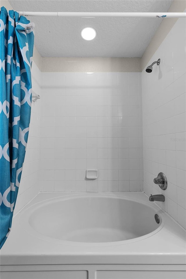 bathroom featuring shower / tub combo with curtain and a textured ceiling