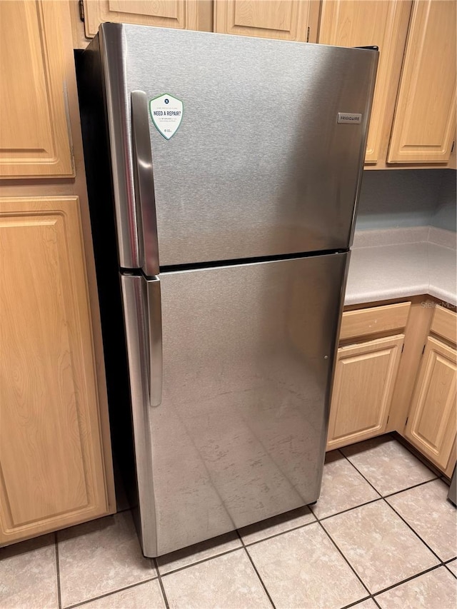 kitchen featuring light tile patterned flooring, light brown cabinets, and stainless steel refrigerator