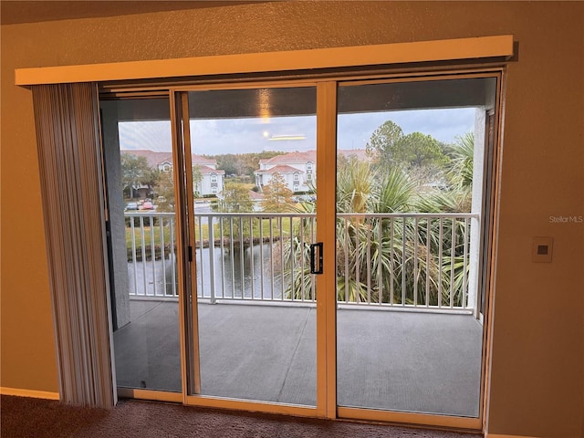 doorway with carpet floors and a water view