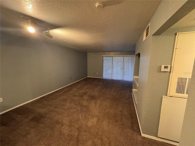 unfurnished room featuring dark carpet, rail lighting, and a textured ceiling