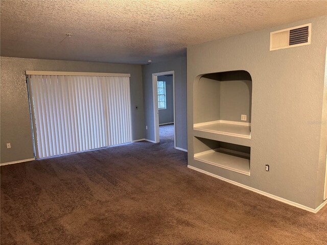 empty room featuring dark carpet and a textured ceiling