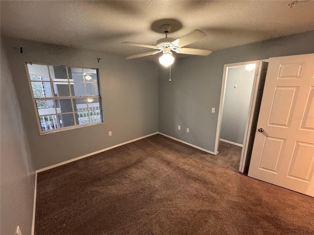 unfurnished bedroom with ceiling fan, a textured ceiling, and dark colored carpet