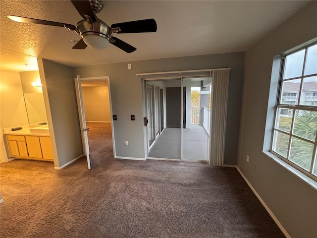 unfurnished bedroom with carpet flooring, a textured ceiling, multiple windows, and access to outside