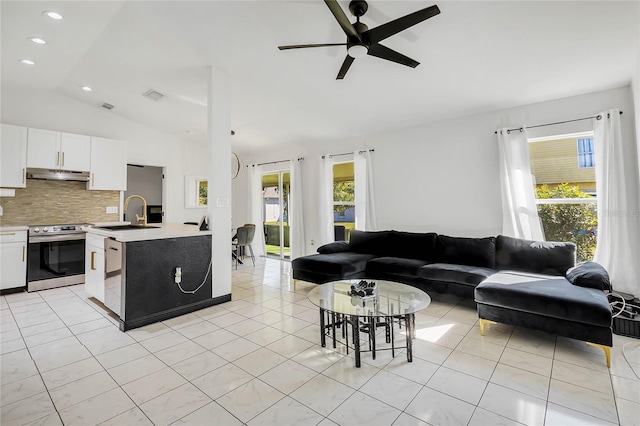 tiled living room with ceiling fan, sink, and lofted ceiling