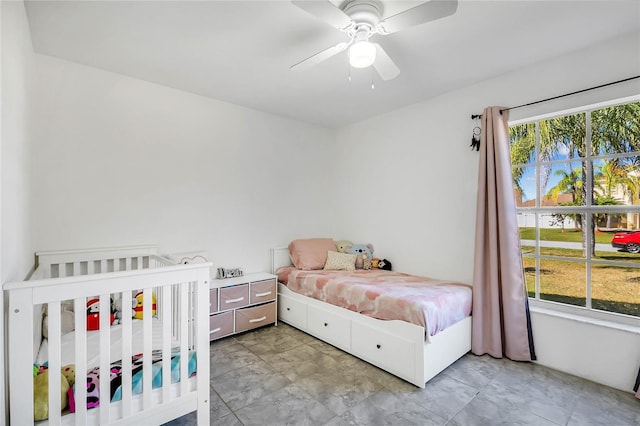 bedroom with ceiling fan and a crib