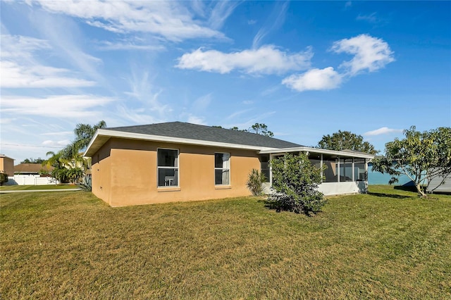 rear view of house with a lawn and a sunroom