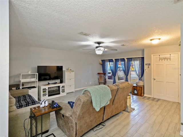 living room with ceiling fan, light hardwood / wood-style floors, and a textured ceiling